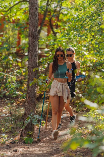 在阳光明媚的日子里 两个高加索女人朋友在山上的树林里徒步旅行 — 图库照片