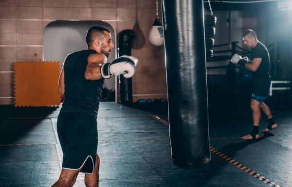 Αθλητικός Άντρας Χτυπάει Μια Τσάντα Γάντια Πυγμαχίας Στο Γυμναστήριο Έννοια — Φωτογραφία Αρχείου