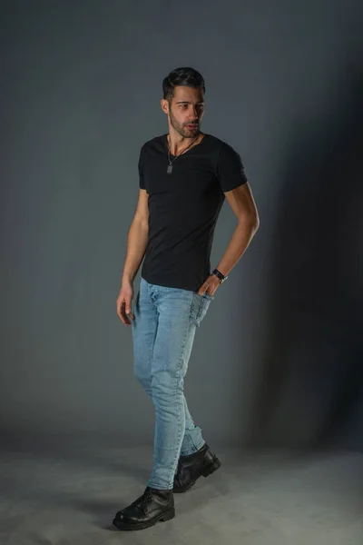 Studio photoshoot of a good-looking man posing in jeans and black shirt