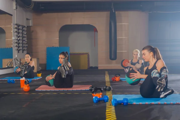 stock image Attractive sports girls practicing abs exercise with med ball in a group fitness workout