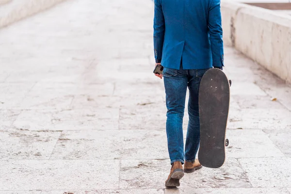 シティブリッジを歩きながらスケートボードを保持しているビジネスマンを自信を持って — ストック写真