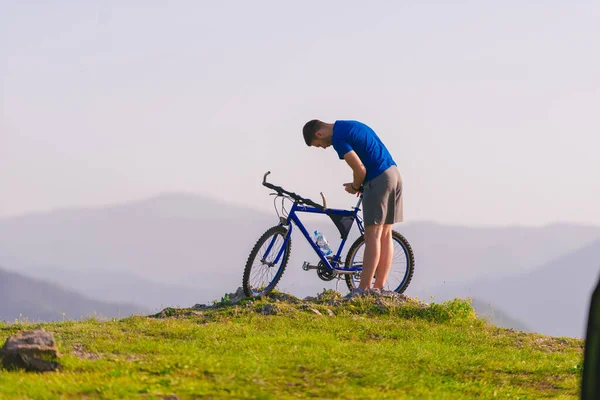 适合骑自行车的山地骑手骑着自行车在山顶上的青草地上行驶 — 图库照片