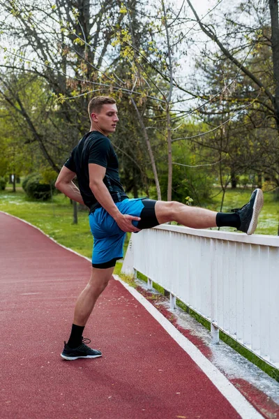 Läufer Schwarzer Sportbekleidung Streckt Beine Vor Dem Morgendlichen Training Öffentlichen — Stockfoto