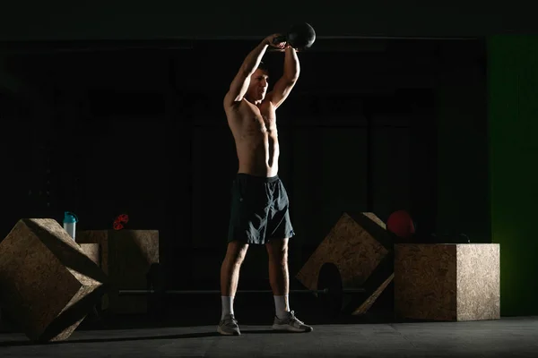 High contrast photo of a healthy fitness guy doing workout using a kettlebell