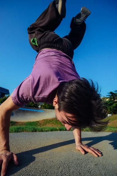 市のスケートボードパークでハンドスタンドをしている間 彼の体を支えるスポーツマン — ストック写真