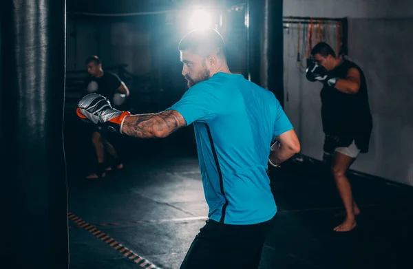 Male boxer as exercise for the big fight. Boxer hits punching bag. Young masculine male athlete