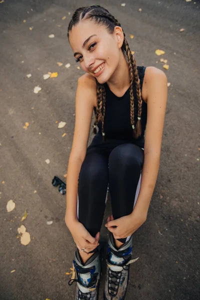 Sorprendente Joven Con Trenzas Pelo Posando Patines Mientras Está Sentada —  Fotos de Stock