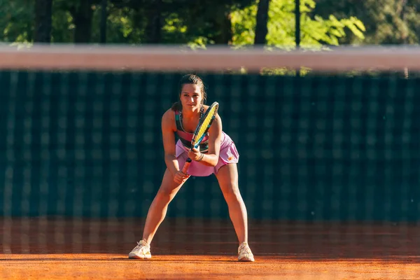 女子テニスプレーヤーは粘土コートでテニスゲームをプレイするのに役立つ返すのを待っています — ストック写真