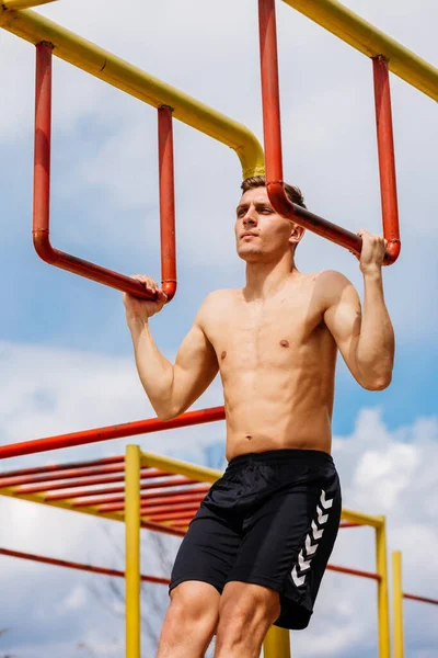 Jimnastik Salonunun Barlarında Sallanan Atletik Genç Adam Gülümsüyor — Stok fotoğraf
