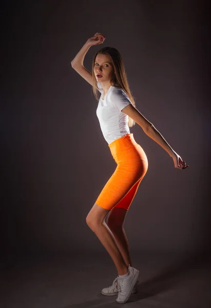Hezké Sportovní Dívka Krátkými Oranžové Legíny Pózovat Izolované Tmavém Pozadí — Stock fotografie