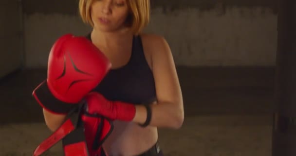 強い女の子はトレーニングのためにボクシングの手袋をはめている — ストック動画