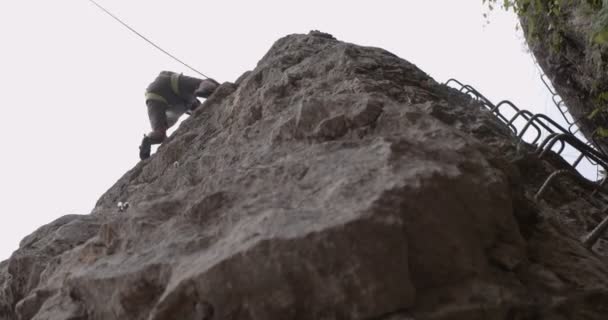 スポーティで先輩が大きな岩の上を登っている — ストック動画