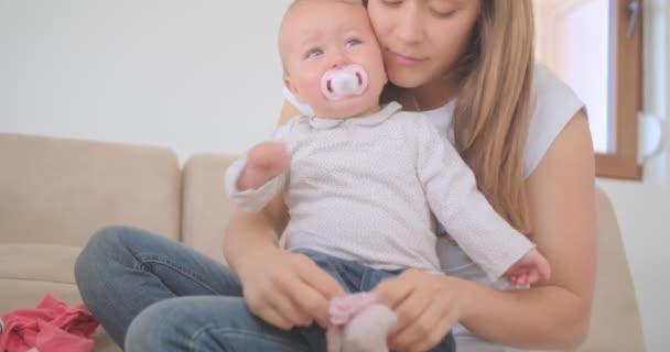 Schöne Mutter Zieht Socken Über Ihr Baby — Stockvideo