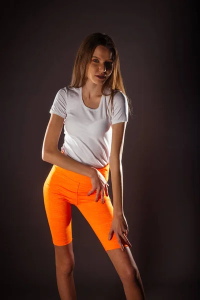 Mooie Sport Meisje Met Korte Oranje Legging Poseren Geïsoleerd Donkere — Stockfoto