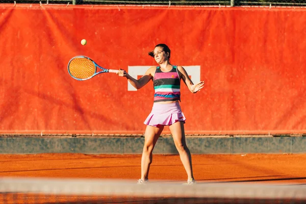 若いフィット女性は早朝にオレンジ色のテニス場でテニス屋外でプレイ — ストック写真