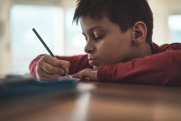 Joven chico escribiendo tarea — Foto de Stock