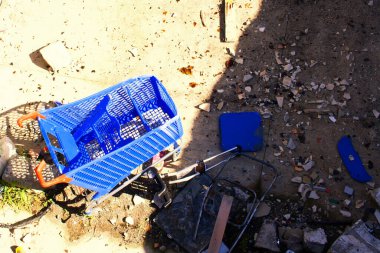 Terk edilmiş ve kırılmış bir süpermarket arabası. Terk edilmiş bir yerde, çöp yığını içinde..