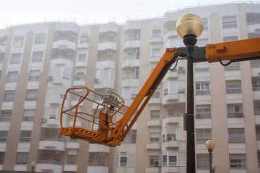 İnşaat asansörünün bir kısmı çok katlı bir binanın arka planında, sisli bir havada..