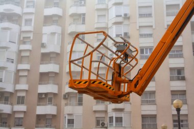 İnşaat asansörünün bir kısmı çok katlı bir binanın arka planında, sisli bir havada..