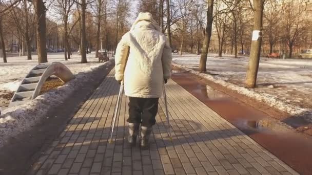 Mulher madura em muletas em um parque da cidade — Vídeo de Stock