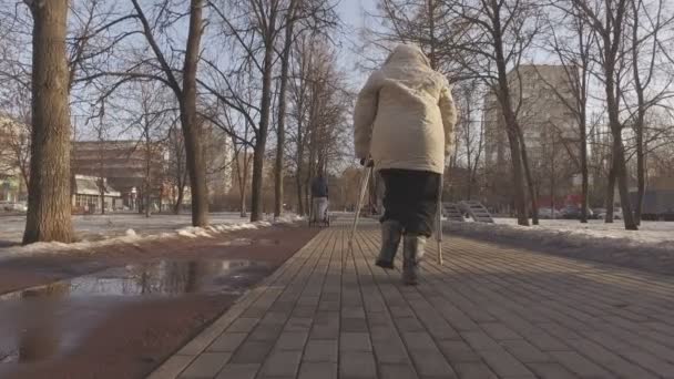 Rijpe vrouw op krukken in een stadspark — Stockvideo