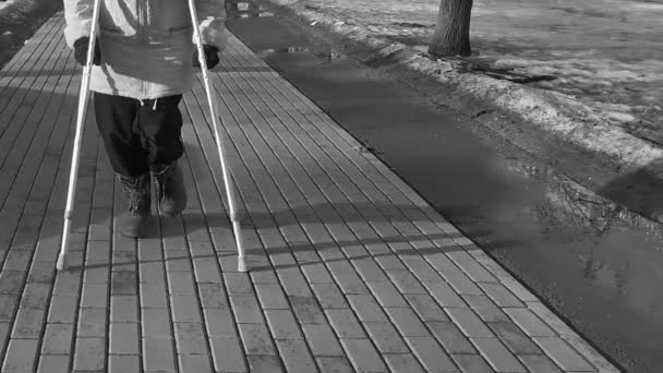 Зрелая женщина на костылях в городском парке — стоковое видео