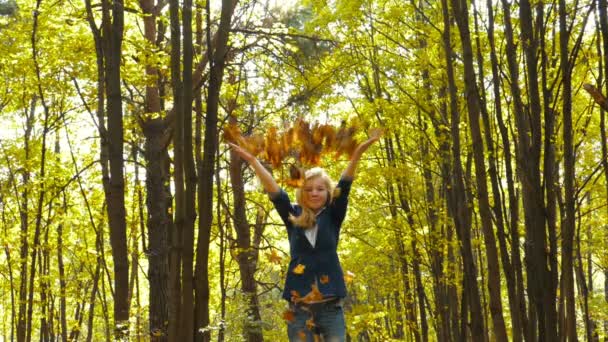 Chica lanzando hojas en otoño en cámara lenta — Vídeos de Stock