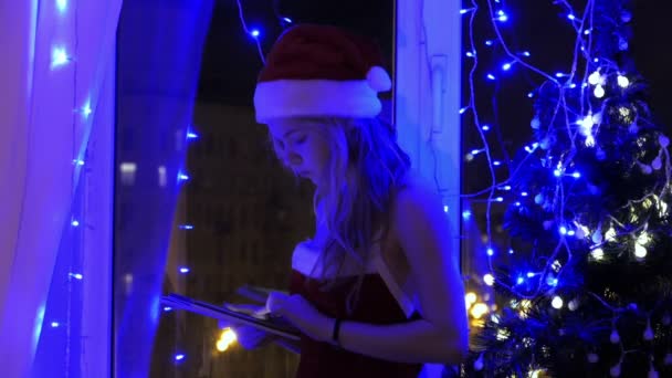 Blond tjej i santa mössa med en tablett — Stockvideo