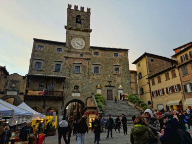 CORTONA, İTALYA - 7 Aralık 2025: Burası Cortona, Toskana 'daki Piazza della β bblica. Ana bina, antik Roma harabelerinin üzerine inşa edilen kendine özgü saat kulesiyle ortaçağ Comunale Sarayı 'dır (belediye binası).
