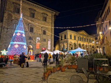 CORTONA, İtalya - 7 Aralık 2025: Piazza Signorelli, Cortona 'daki Noel pazarının manzarası. Başlıca binalar ortaçağ Casali Sarayı ve 19. yüzyıl Sinyorelli Tiyatrosu 'dur.