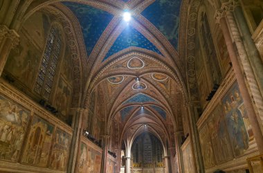 ASSISI, ITALY - 10 Aralık 2025: Assisi, İtalya 'daki Yukarı Francis Bazilikasının iç mimarisi, canlı Gotik mimarisi ve Giotto gibi ustalar tarafından 13 / 14. yüzyıl freskleri ile ünlüdür.