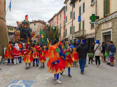 FOIANO DELLA CHIANA - 2 Mart 2025: İtalya 'nın Foiano della Chiana' daki en eski karnavalında çocuklar ve yetişkinler tarafından giyilen renkli kostümler. Kalabalık ve yüzenlerle dolu canlı bir sokak geçidi.
