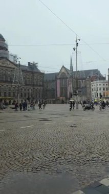 AMSTERDAM, NETHERLANDS - 9 HAZİRAN 2026: 4K yoğun kar yağışı görüntüleri Amsterdam, Baraj Meydanı 'nda. Kraliyet Sarayı ve anıtla karda yürüyen turistler görülüyor.