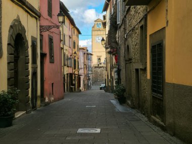 Uzaktan görülebilen ortaçağ saat kulesiyle tarihi İtalyan köyü Vitorchiano 'da büyüleyici bir sokak manzarası.