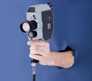 Mavi kağıt arka plan ile kırma ve retro kamera tutarak erkek el