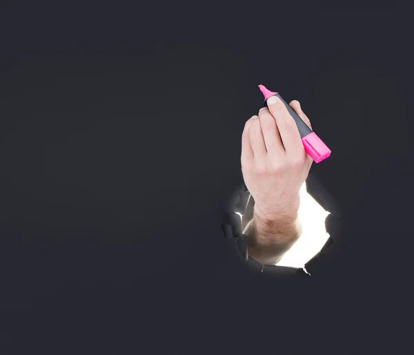 Mão masculina rompendo o fundo de papel cinza e segurando marcador — Fotografia de Stock