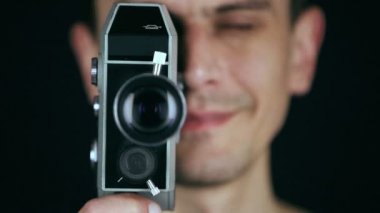 Siyah arka plan üzerine film çekmek için bir retro film kamerası kullanan genç yetişkin adam. Eski film etkisi. HD
