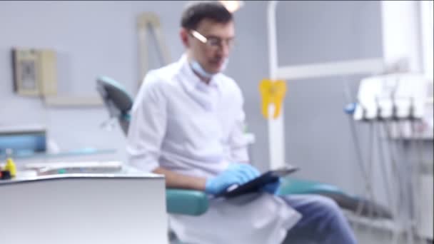 Biuro dentysta. Lekarz siedzi w pobliżu fotelu — Wideo stockowe