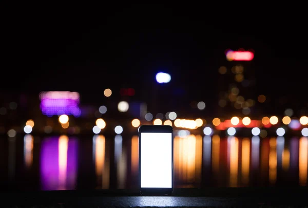Телефон на фоне города ночью — стоковое фото