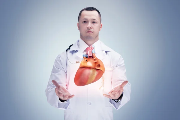 Docteur avec stéthoscope et cœur sur les mains. fond gris. Haute résolution . — Photo