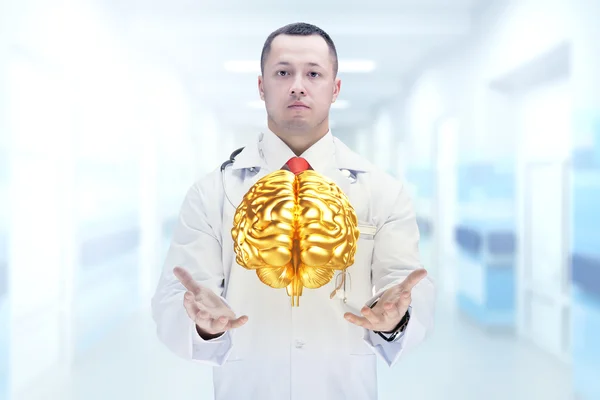 Doctor con estetoscopio y cerebros dorados en las manos en un hospital. Alta resolución . — Foto de Stock