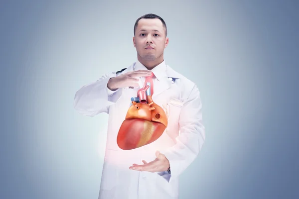 Doctor con estetoscopio y corazón en las manos. fondo gris. Alta resolución . — Foto de Stock