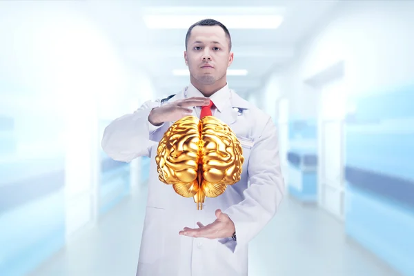 Arts met stethoscoop en gouden hersenen op de handen in een ziekenhuis. Hoge resolutie. — Stockfoto