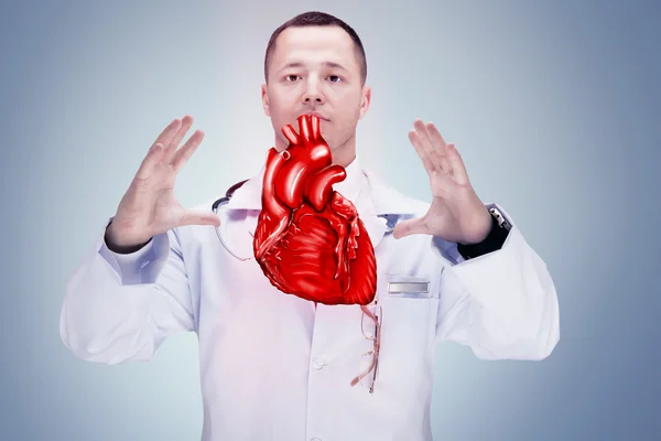 Doctor with stethoscope and heart on the hands. gray background. High resolution. — Stock Photo, Image