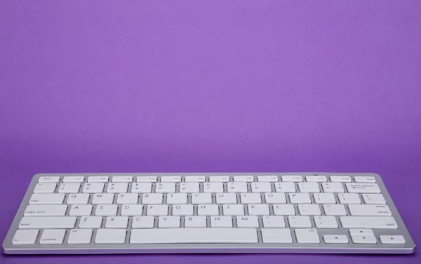 Teclado do computador em fundo violeta — Fotografia de Stock