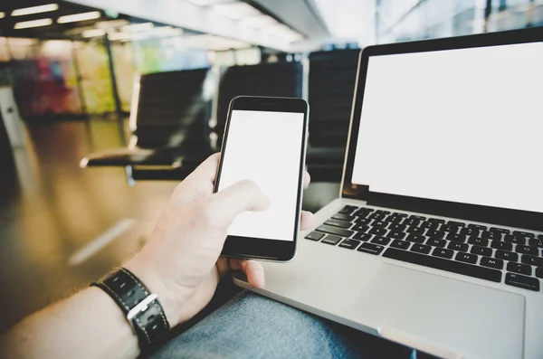 Junger Mann benutzt Notebook oder Laptop und Handy am Flughafen. — Stockfoto