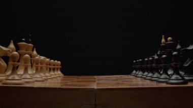 Yakın plan satranç oyunu. Satranç tahtasındaki oyundan önce hazırlanan tahta satranç taşları. Kamera satranç tahtası boyunca hareket eder. Yüksek kalite 4k görüntü
