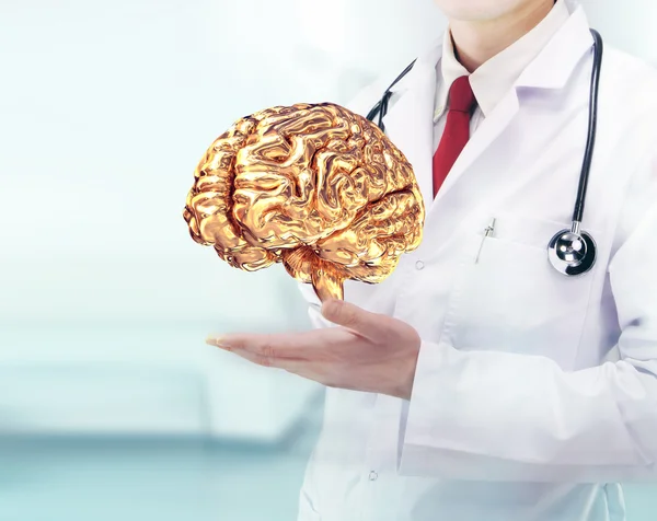 Médecin avec stéthoscope et cervelle dorée sur les mains dans un hôpital — Photo