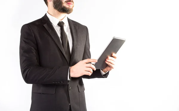 Hipster hombre en un traje clásico aislado sobre un fondo blanco con una tableta en la mano — Foto de Stock