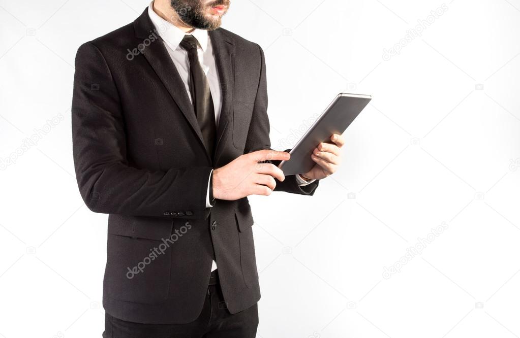 Hipster man in a classic suit isolated on a white background with a tablet in hand